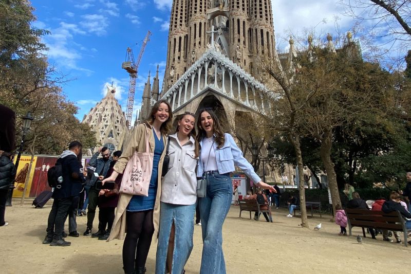 three female students standing together at a landmark